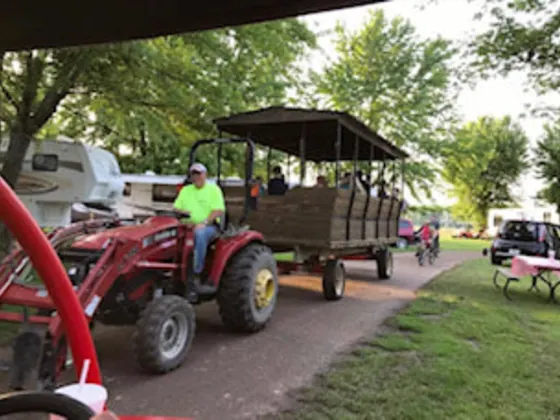 A tractor pulling the hay wagon ride through the campground